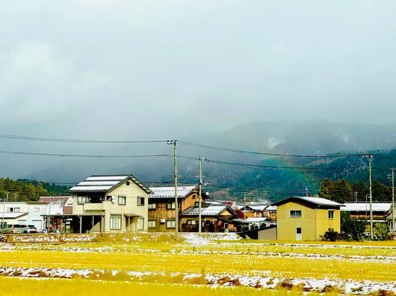 車窗外覆上一層薄雪的村落與彩虹